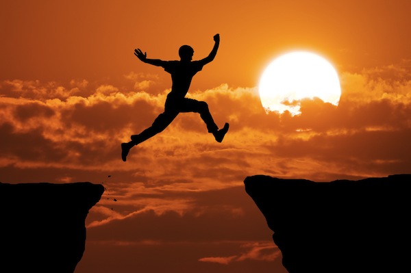 Man leaping from one cliff edge to another