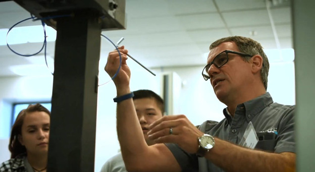 Man speaking to people while holding cords