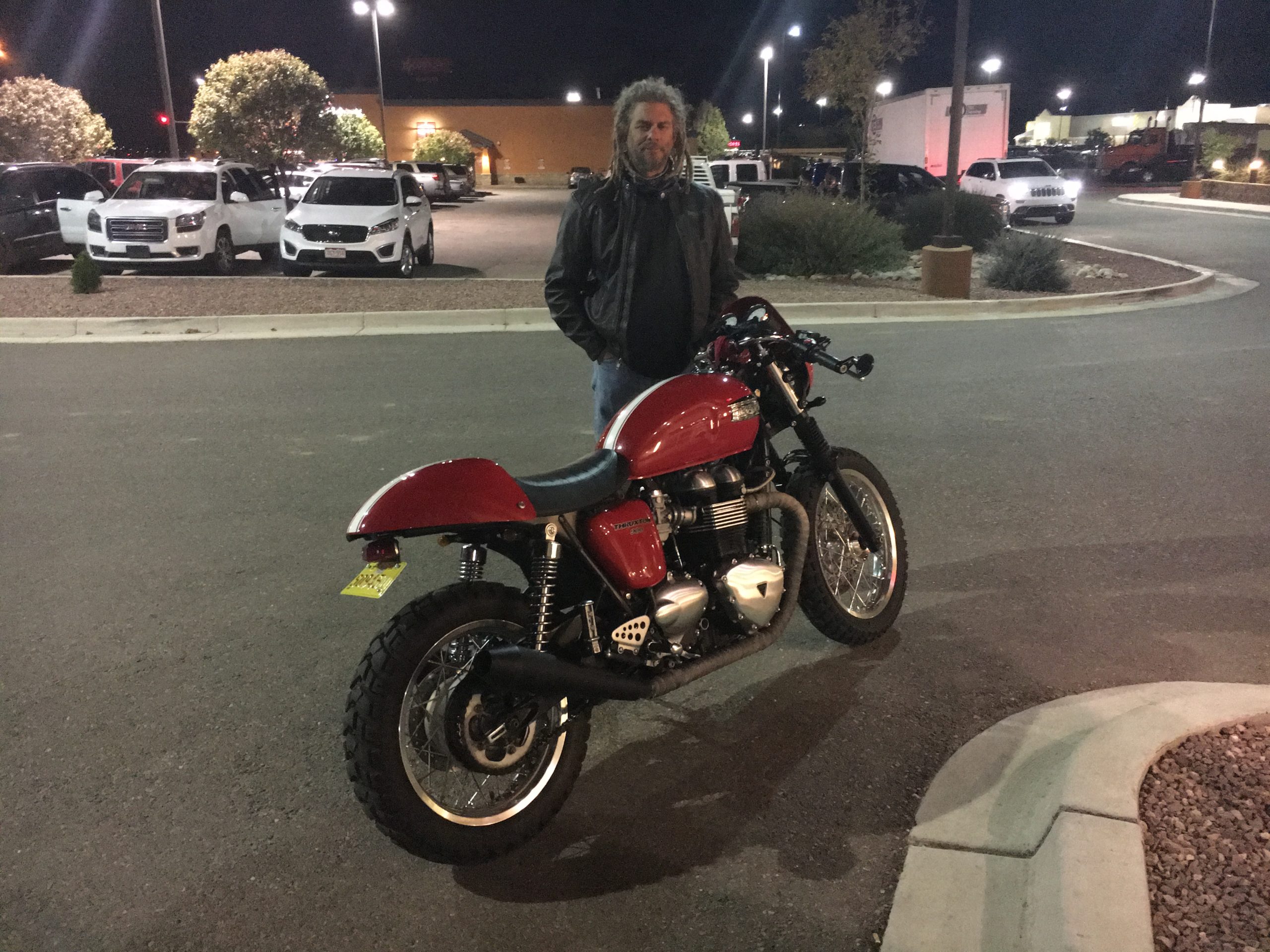 Man standing with motorcycle in parking lot