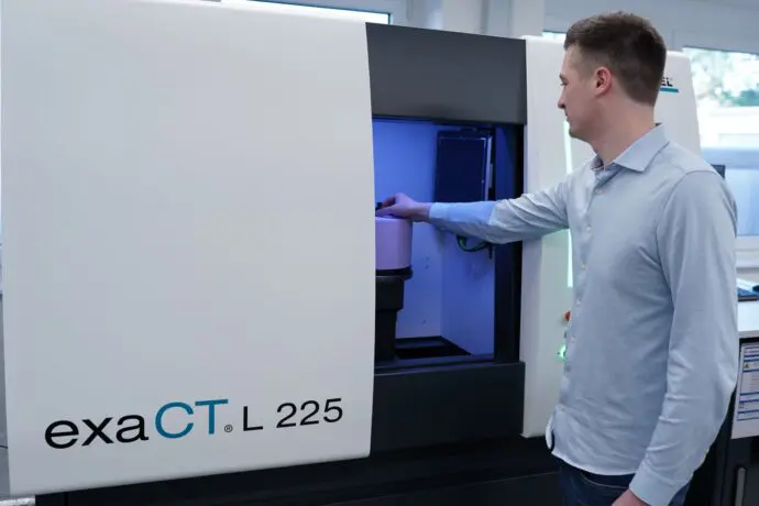 A technician operates the exaCT L 225 machine, preparing it for precise scanning in a modern lab environment.